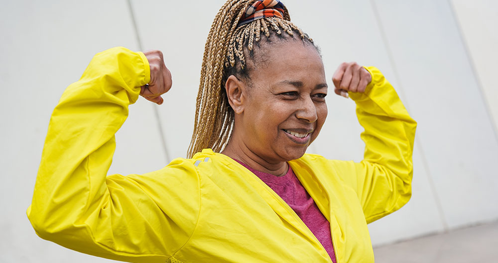 Senior african woman showing biceps muscle during sport workout in the city