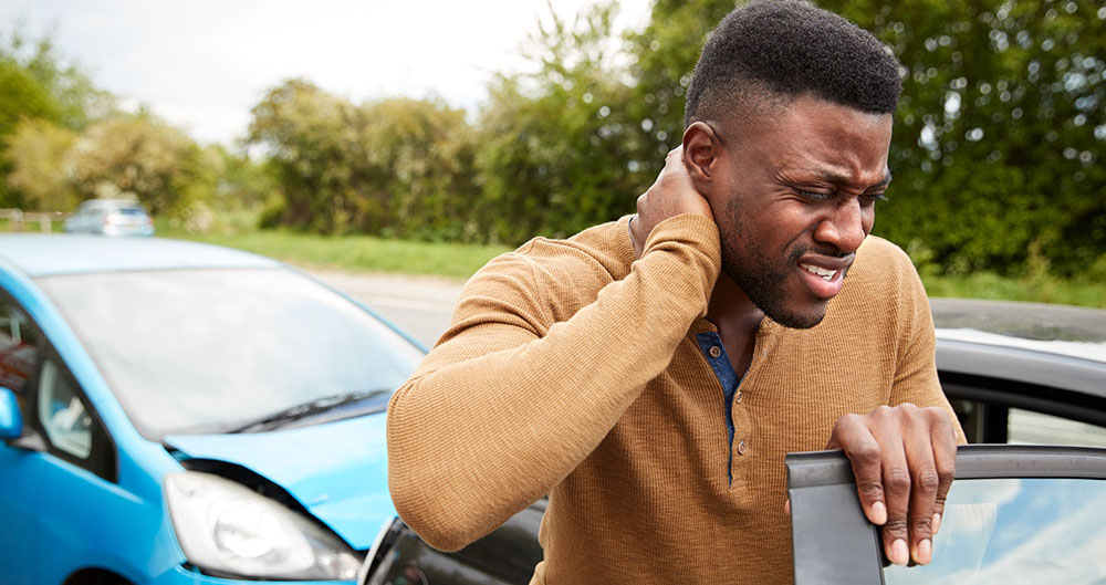 Male Motorist With Whiplash Injury In Car Crash Getting Out Of Vehicle